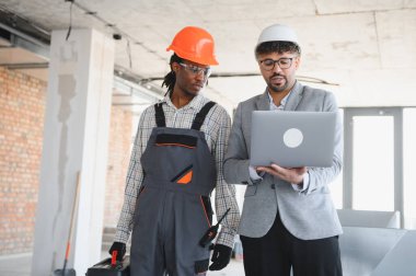 İnşaat alanı teftişi sırasında bir mimarın dizüstü bilgisayarında bina planlarını göstermesi