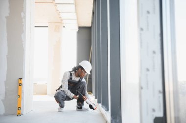 Kaliteli inşaat işçisi pencere çerçevesine dolgu macunu sürüyor, inşaat halindeki bir binaya hava geçirmez ve hava geçirmez kurulum sağlıyor