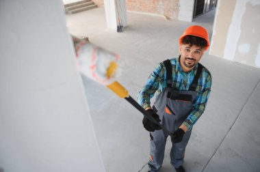 İnşaat halindeki bir binanın duvarlarını teleskopik boya rulosuyla boyayan Arap inşaatçı yenileme ve bakım becerilerini sergiliyor.
