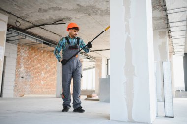 Arap müteahhit inşaat sahasındaki bir sütunun alçısını inceliyor, kaliteyi ve standartları sağlama alıyor.