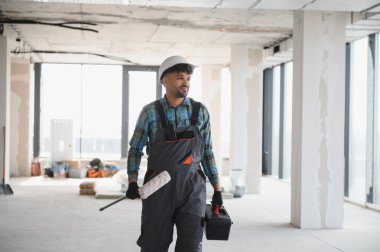 Yapım aşamasındaki modern bir binada yürüyen Arap mühendis, projeye odaklanırken bir alet çantası ve boya silindiri taşıyordu.