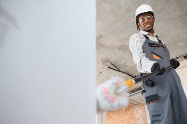 İnşaat işçisi inşaat halindeki patenle duvar boyuyor..