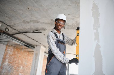 Ev tadilatı sırasında duvarın dikey görünmesini sağlamak için ruh seviyesini kullanan Afrikalı Amerikalı inşaatçı