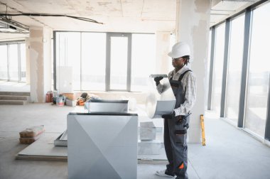 Afrikalı Amerikalı inşaat işçisi inşaat halindeki bir binada havalandırma sistemi için metal havalandırma boruları kuruyor.