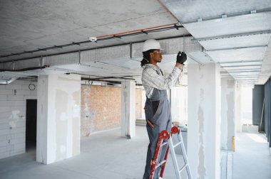 Afrika kökenli Amerikalı inşaat işçisi inşaat halindeki bir binaya havalandırma sistemi kuruyor.