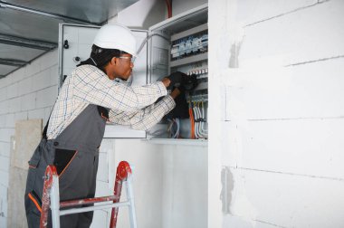 Elektrikçi yeni binaya elektrik paneli yerleştiriyor, güvenli ve verimli güç dağılımı sağlıyor