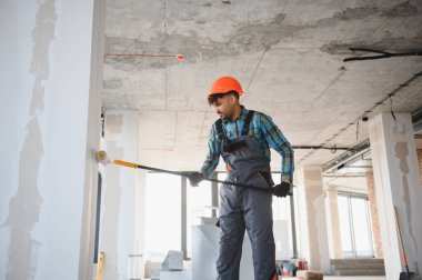 Bir inşaat sahasında ustalıkla çalışan, titizlikle ve titizlikle duvar bitirme görevlerine odaklanan, sert şapkalı bir mühendis.