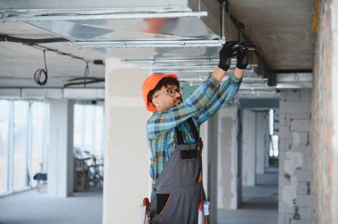 Bir inşaat sahasında havalandırma sistemi kurulumu üzerinde çalışan yetenekli bir elektrikçi gelecekteki binada düzgün hava akışı ve iklim kontrolü sağlıyor.