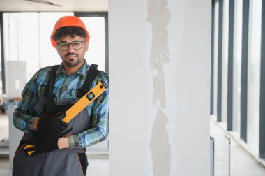 Arap mühendis başlık takıyor ve ruh seviyesini tutuyor. Hassasiyet ve denge odaklı bir inşaat sahasında özenle çalışıyor.