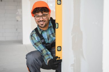 Arap inşaat işçisi, yoğun bir şantiyede dikey duvarları ölçerken ruhsal düzeyi kullanıyor.