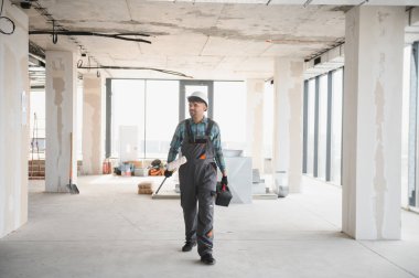 İnşaat halindeki bir binanın içinde iş aletleri taşıyan ve güvenlik kaskı takan bir Arap mühendis.