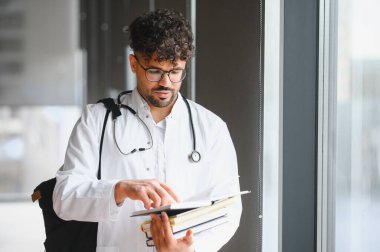 Üniversite koridorunda ders kitaplarını inceleyen odaklanmış tıp öğrencisi sınavlara ve tıp kariyerine hazırlanıyor.