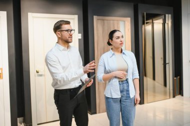 Bir ev geliştirme mağazasında kadınlara iç tasarım seçenekleri gösteren satıcı, farklı ürünlerin özelliklerini ve faydalarını tartışıyor