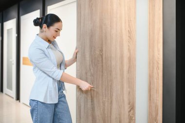Müşteri yeni bir apartman kapısının malzemelerini incelerken aynı zamanda kaliteyi ve stili göz önünde bulundurarak ev dekorasyonu mağazasında seçenekleri araştırıyor.