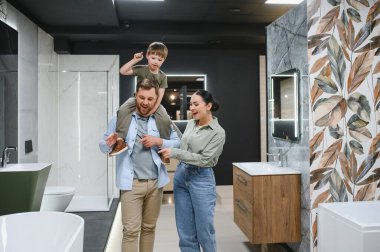 Gülümseyen aile seramik fayanslar ve banyo armatürlerini bir su tesisatçısında seçiyor, birlikte vakit geçiriyorlar.