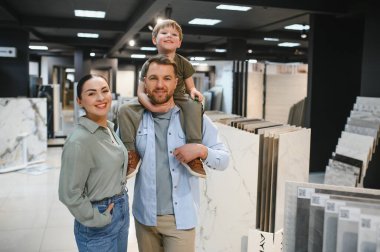 Gülümseyen aile modern bir tesisat dükkanında banyo veya mutfak yenilemesi için seramik fayanslar ve malzemeler seçiyor.