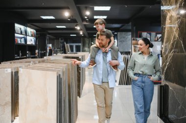 Mutlu aile ev yenileme için seramik fayanslar seçerken seçeneklerle dolu modern bir hırdavatçıda birlikte vakit geçiriyorlar.