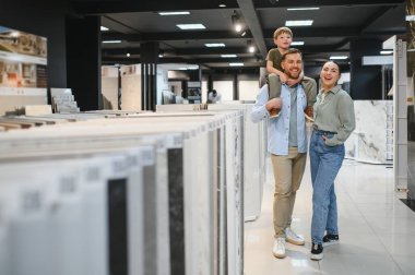 Mutlu bir aile modern bir hırdavatçıda seramik fayanslar seçiyor ve birlikte vakit geçiriyorlar.