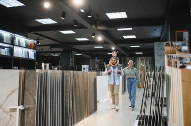 Mutlu bir aile bir hırdavatçıda yürüyor, dairelerini yenilemek için seramik fayanslar seçiyorlar.