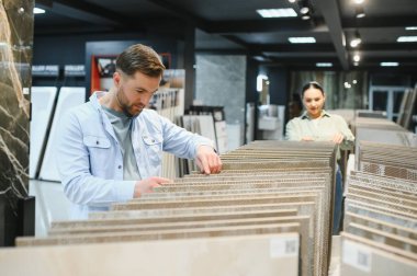 Müşteriler tesisat ve fayans dükkanlarından seramik fayanslar seçiyor, yenileme projeleri için örnekler inceliyorlar.