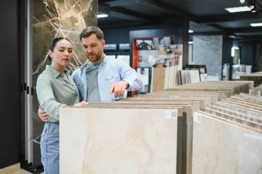 Hırdavatçıdaki seramik fayanslara göz atan çift, yeni ve şık bir yer için ev yenileme projelerini dikkatlice planlıyorlar.