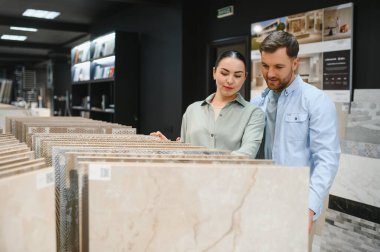 Bir hırdavatçıda seramik fayanslar seçen çift, ev yenileme projeleri için çeşitli seçenekleri araştırıyor