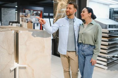 Bir hırdavatçıda seramik fayans gösteren mutlu çift, ev yenileme ve iç tasarım hakkında tartışıyorlar