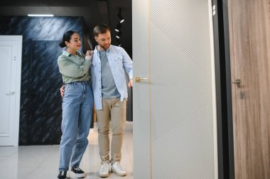Müşteriler daireleri için yeni bir kapı seçerken, bir inşaat malzemeleri mağazasında seçenekleri değerlendiriyor, tarzları ve kaliteyi tartışıyor