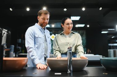 Mutlu çift yeni bir lavabo seçiyor. Bir su tesisatı dükkanında, seçeneklerini tartışıyor ve evlerinin tadilatı için karar veriyorlar.