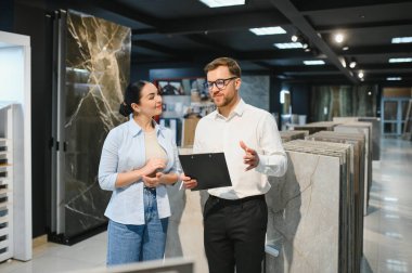Profesyonel satıcı elinde farklı seramik örnekleri gösteren bir pano tutuyor.