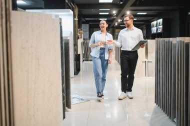 Satıcı, kadın müşteriye seramik seramik seramik dükkanında yürüyen farklı seramik modeller gösteriyor.