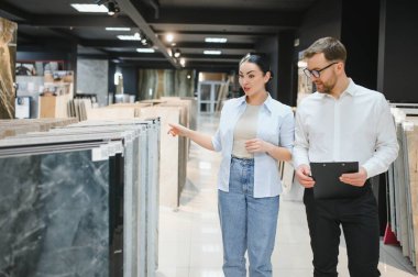 Modern bir tesisat ve fayans dükkanında seramik fayanslar seçen kadın müşterilere danışmanlık