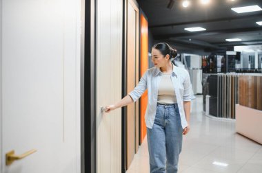 Kadın iç tasarım unsurlarını seçiyor, hırdavatçıda kapı açıyor, kalite ve kolaylıkları kontrol ediyor