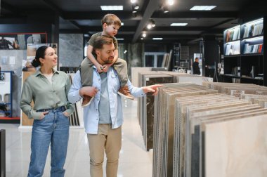 Mutlu aile, seramik fayansları seçerken parlak ve modern bir hırdavatçıda birlikte vakit geçiriyorlar.