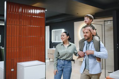 Gülümseyen aile seramik fayansları ve banyo armatürlerini seçiyor. Tesisatçı dükkanında birlikte vakit geçiriyorlar.