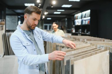 Müşteriler, yenileme projeleri için seramik fayansları bir mağazadan seçerek çeşitli seçenekleri değerlendiriyorlar.