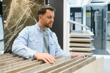 Bir ev geliştirme mağazasında seramik fayansların seçilmesi, bir mutfakta yapılacak yenileme projesi için çeşitli seçenekleri değerlendirmek