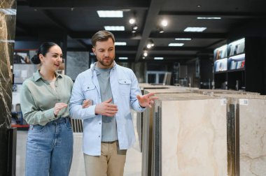 Modern bir mağazada seramik fayanslara göz atıp, ev yenileme seçeneklerini tartışıyorlar. Çeşitli sergilenen parlak sergi salonu