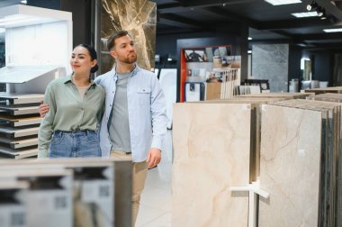 Hırdavatçıda yürüyen genç bir çift dairelerini yenilemek için seramik fayanslar seçiyor.