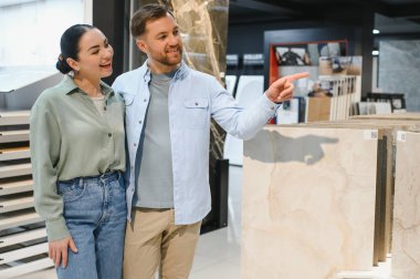 Seramik fayans örneğini işaret eden mutlu çift seramik fayans ve tesisat dükkanında banyo yenileme malzemeleri tartışıyor ve seçiyor.