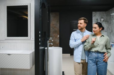 Bir çift seramik fayans ve su tesisatı dükkanında banyo malzemeleri seçiyor, evlerini yenilemeyi planlıyorlar.