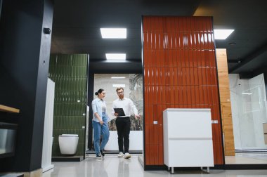 Satış elemanı elinde farklı seramik fayanslar gösteren bir pano tutuyor.