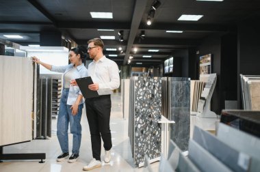 Bina malzemeleri mağazasından seramik fayanslar seçmesini tavsiye eden pano sahibi bir tezgahtar.