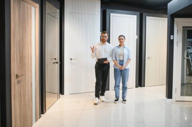 Modern iç kapıları seramik fayans ve su tesisatı mağazasında bayan müşteriye sunan bir satıcı.