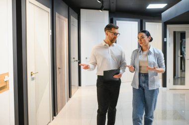 Satıcının kadın müşteriye iç kapılar göstermesi, bir ev geliştirme mağazasından alım tartışması.