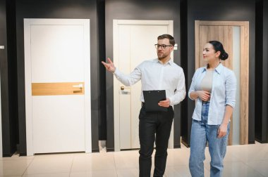 Satış elemanı, modern bir ev dekoratörü mağazasında seçenekleri tartışırken kadın müşteriye iç ve giriş kapılarını seçmesinde yardımcı oluyor.