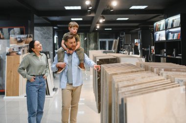 Babasının omuzlarında çocuğu olan bir aile seramik fayans ve su tesisatı dükkanını geziyor, seçenekleri tartışıyor ve kararlar alıyor.