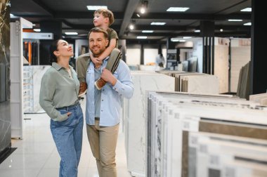 Modern bir hırdavatçıda seramik seramik seramik döşeme seçerek alışveriş yaparken kaliteli vakit geçirmeyi seven mutlu bir aile.