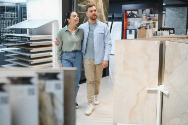 Hırdavatçıda yürüyen genç bir çift dairelerini yenilemek için seramik fayanslar seçiyor.