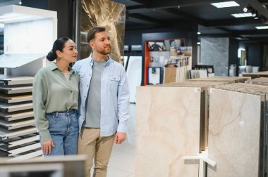 Genç çift bir hırdavatçıda seramik fayanslar seçiyor, ev yenileme projelerini planlıyorlar.